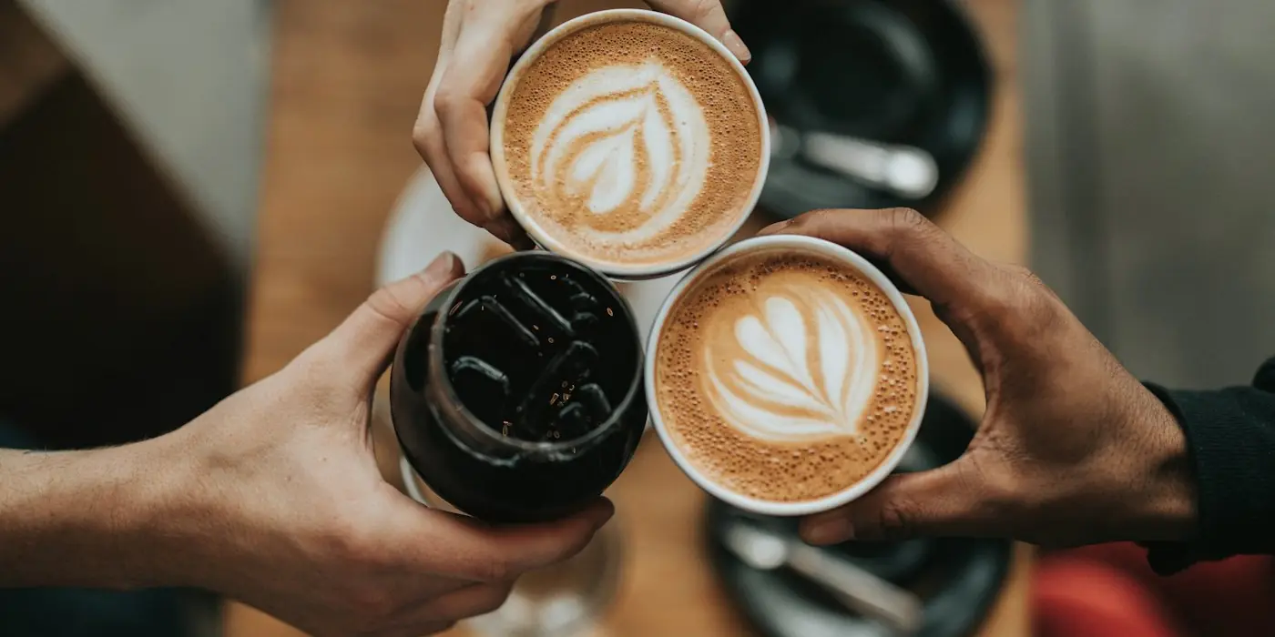 Two hands holding cups of latte art coffee